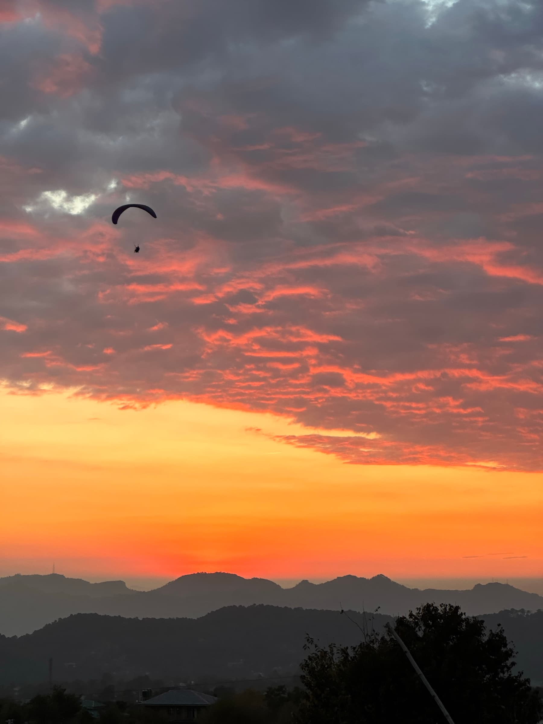 A paraglider crossing a fire orange sunset sky